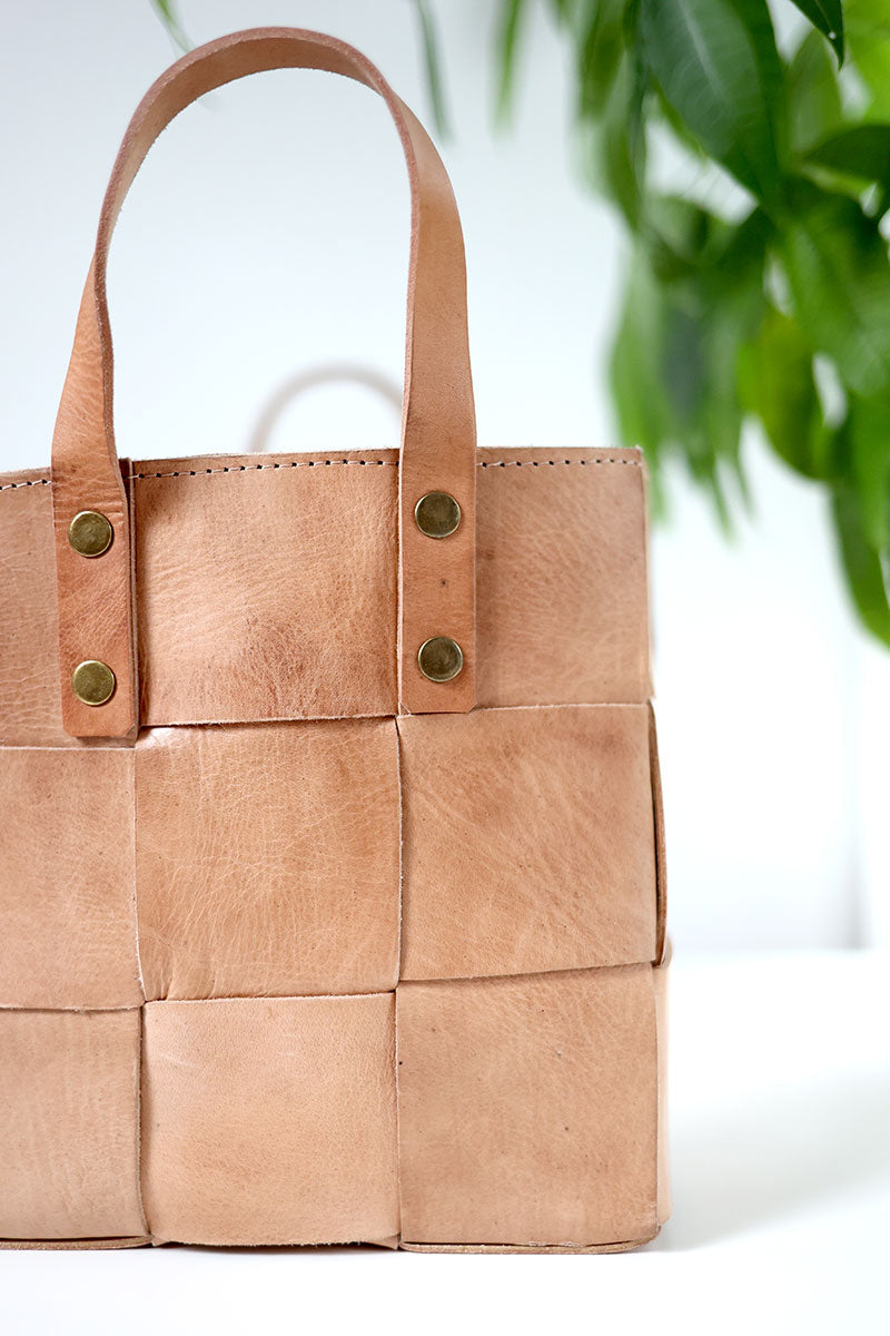 Brown woven handbag with gold buttons on a white background
