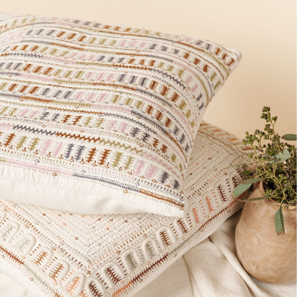 Patterned pillow and blanket with a plant on a neutral background