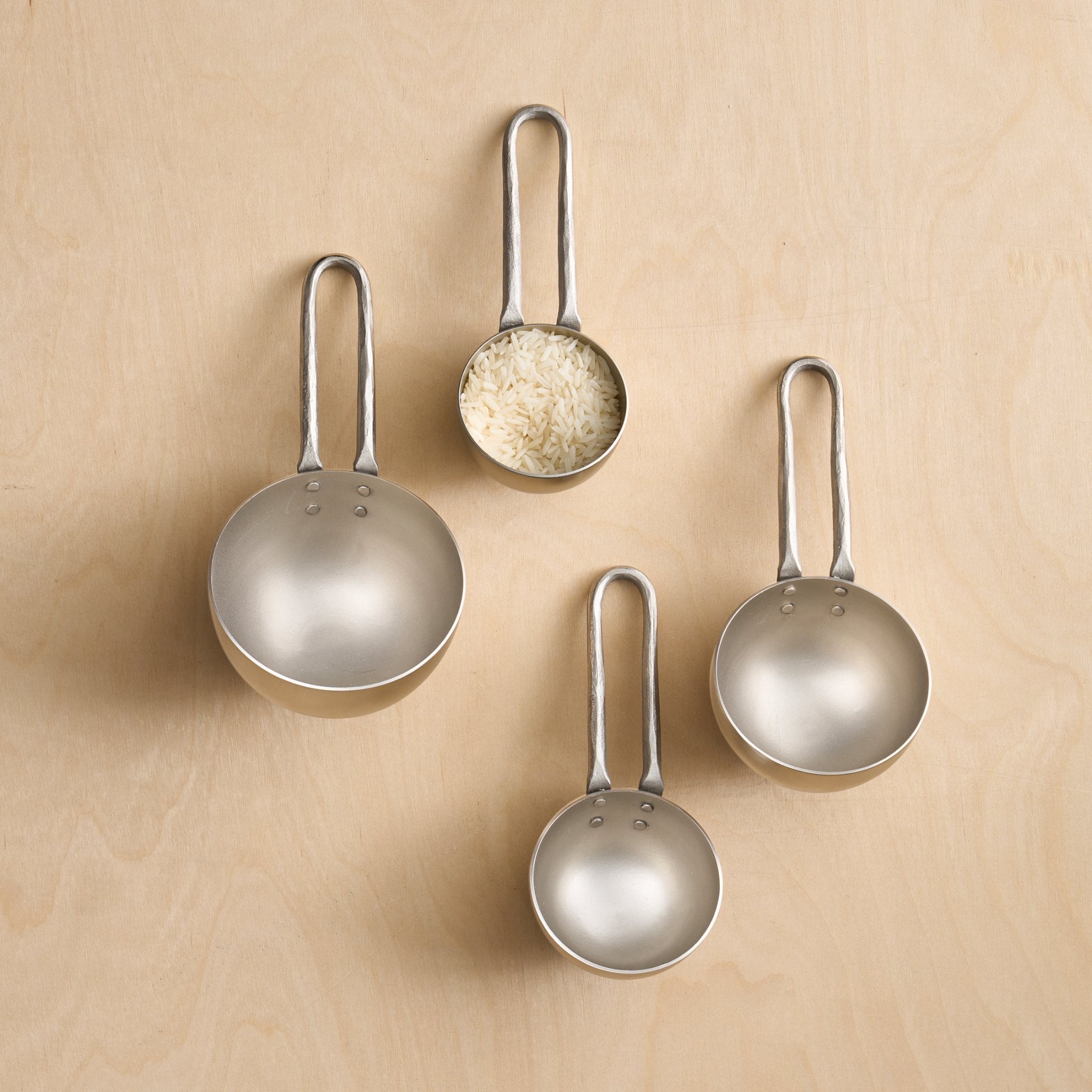 Set of four metallic measuring spoons on a beige background