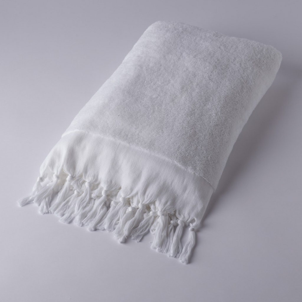 White towel with fringes on a light gray background