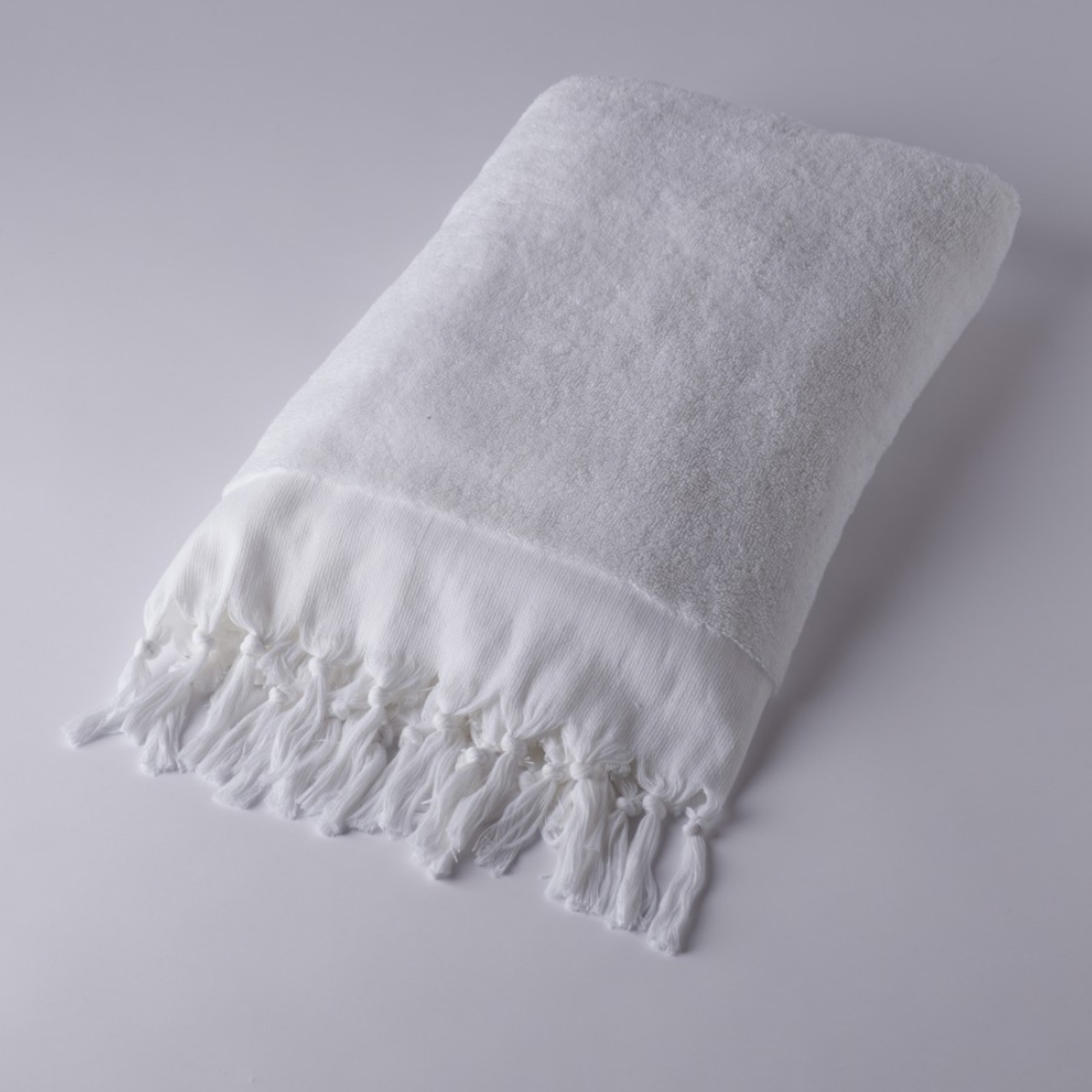 White towel with fringes on a light gray background