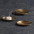 Gold plates with a white candle on a dark textured surface