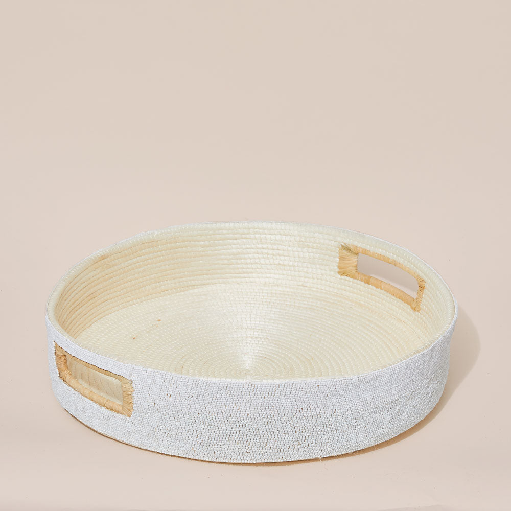 Round beaded woven basket with wooden handles on a beige background