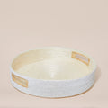 Round beaded woven basket with wooden handles on a beige background