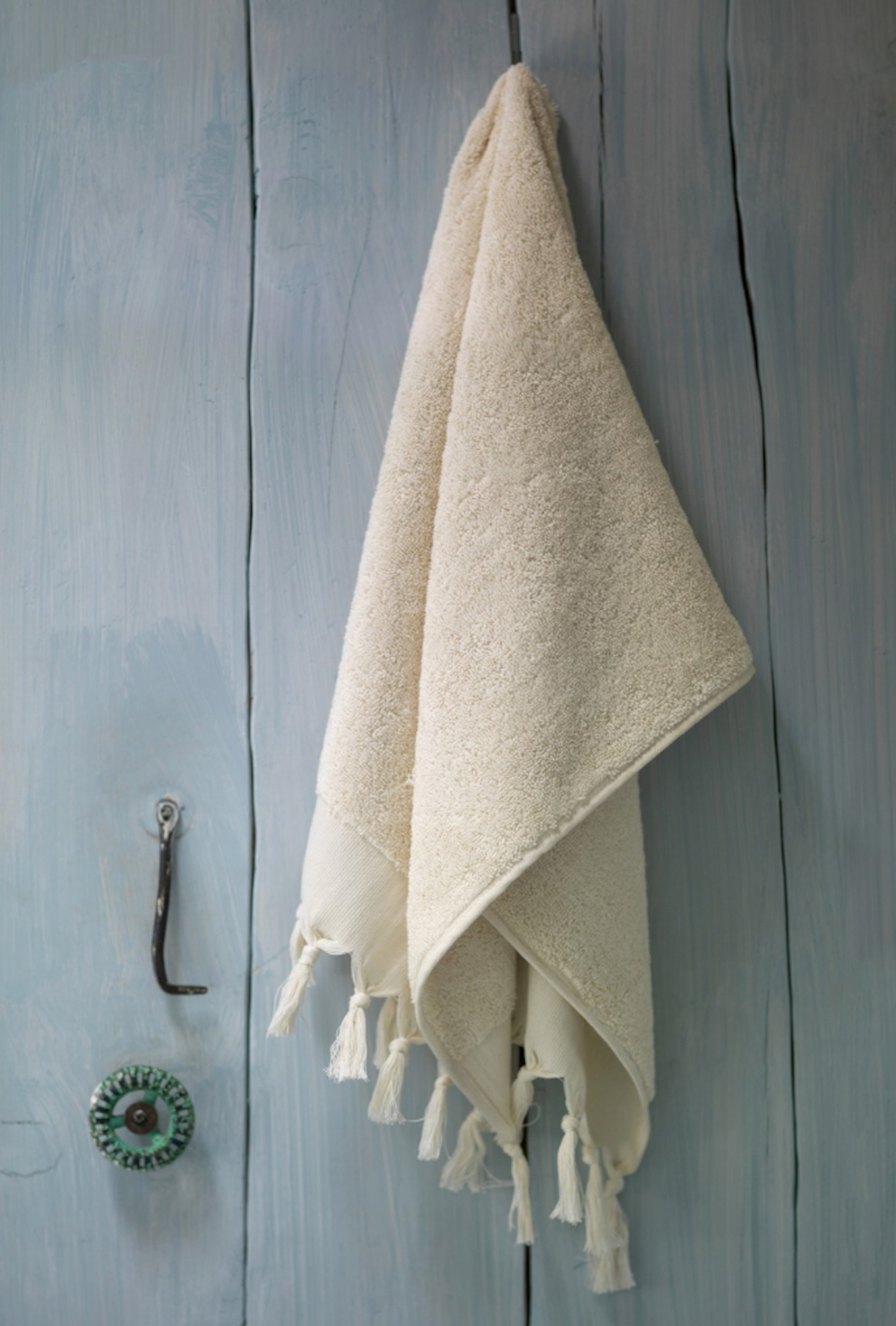 Beige towel with tassels hanging on a wooden door
