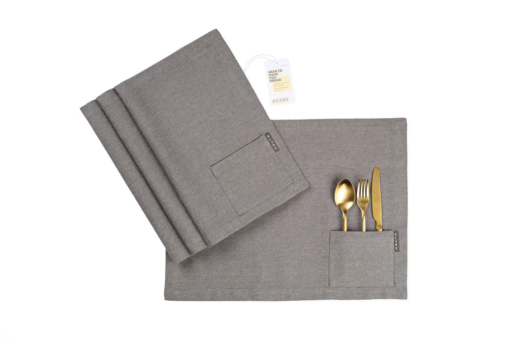 Gray cloth napkin  with cutlery pocket and gold cutlery on a white background