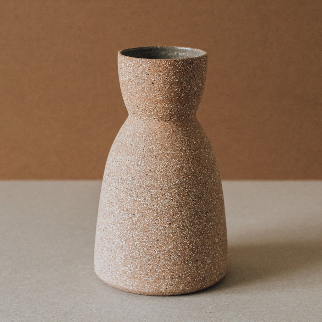 Speckled brown ceramic vase on a neutral background