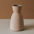 Speckled brown ceramic vase on a neutral background