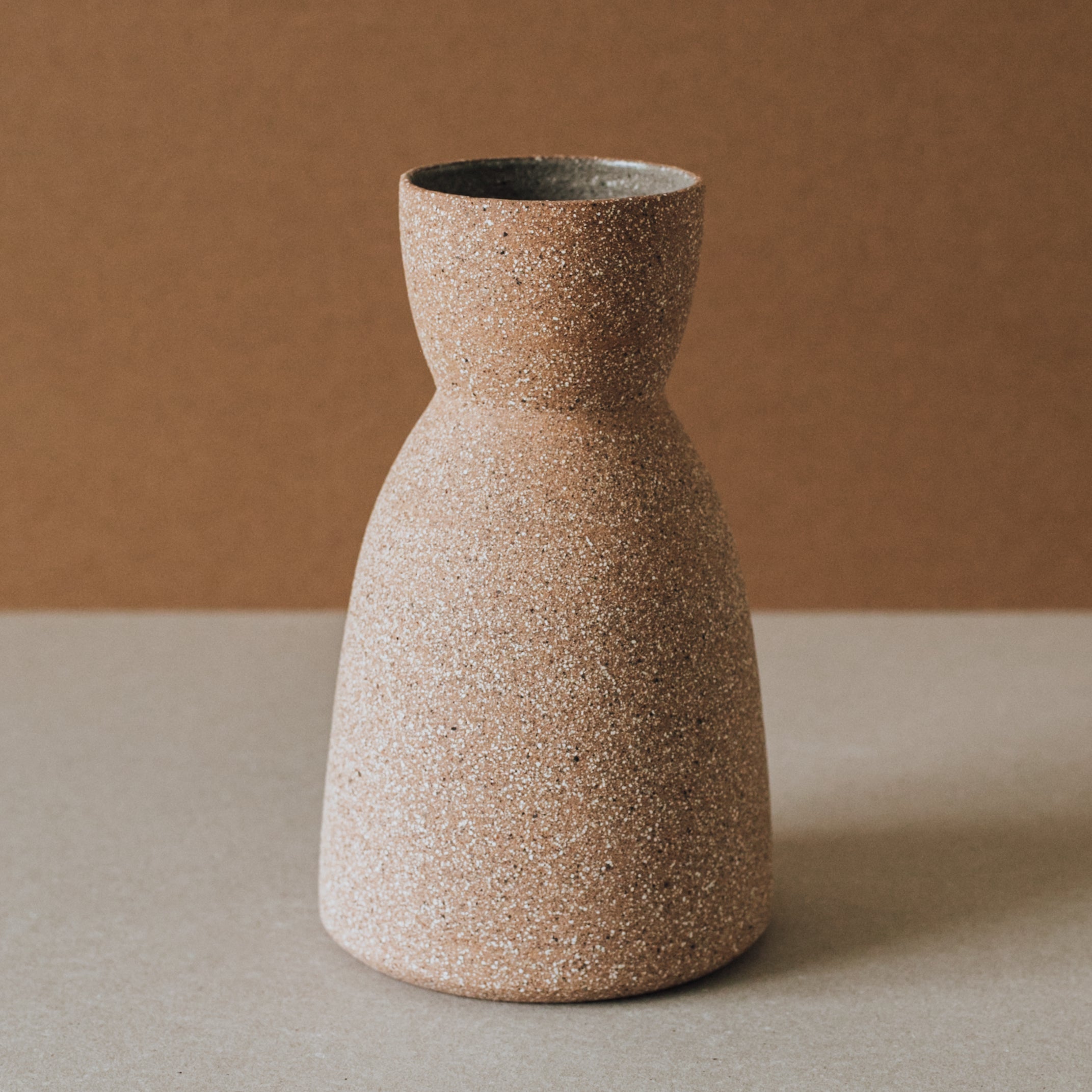 Speckled brown ceramic vase on a neutral background