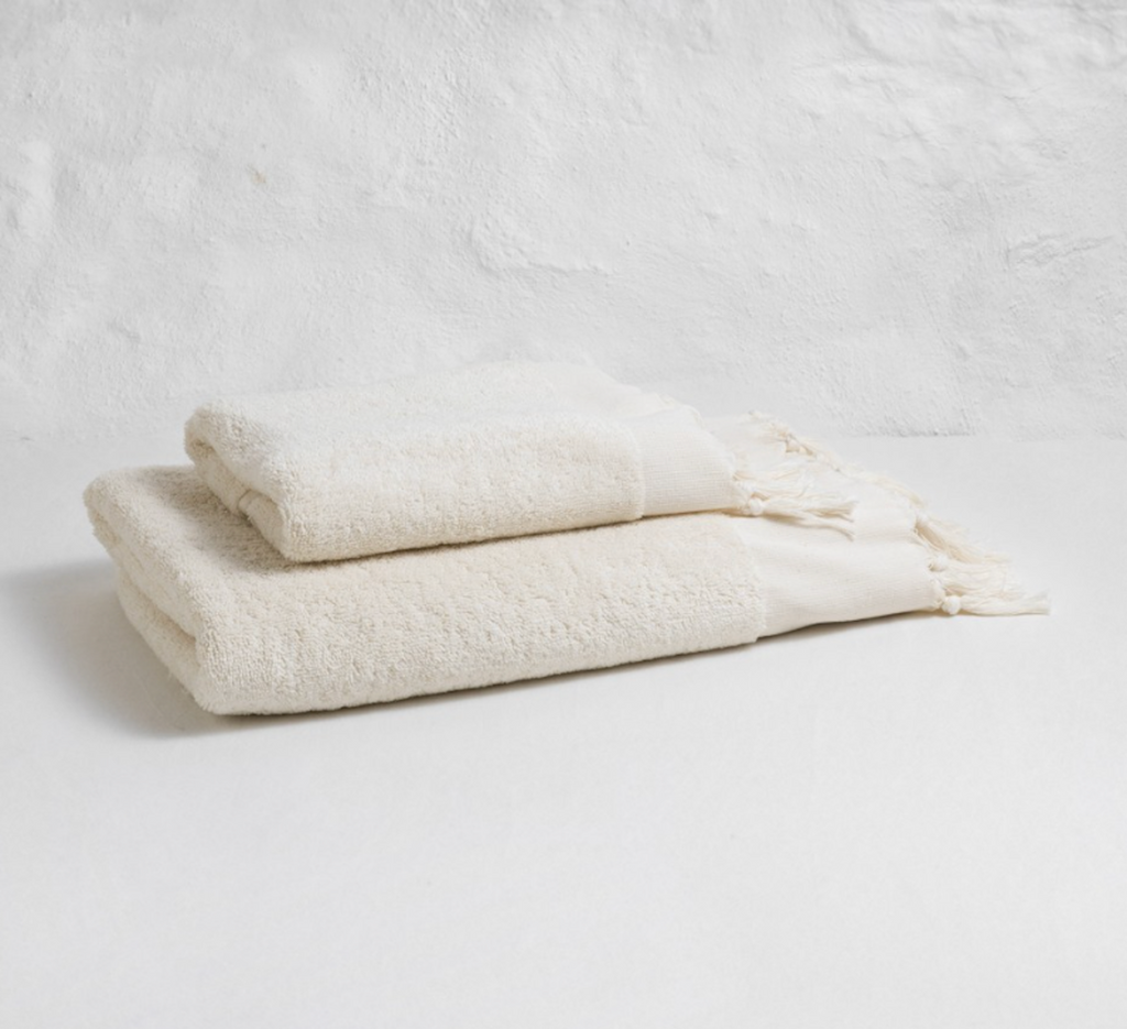 Two cream-colored textured towels on a light gray background