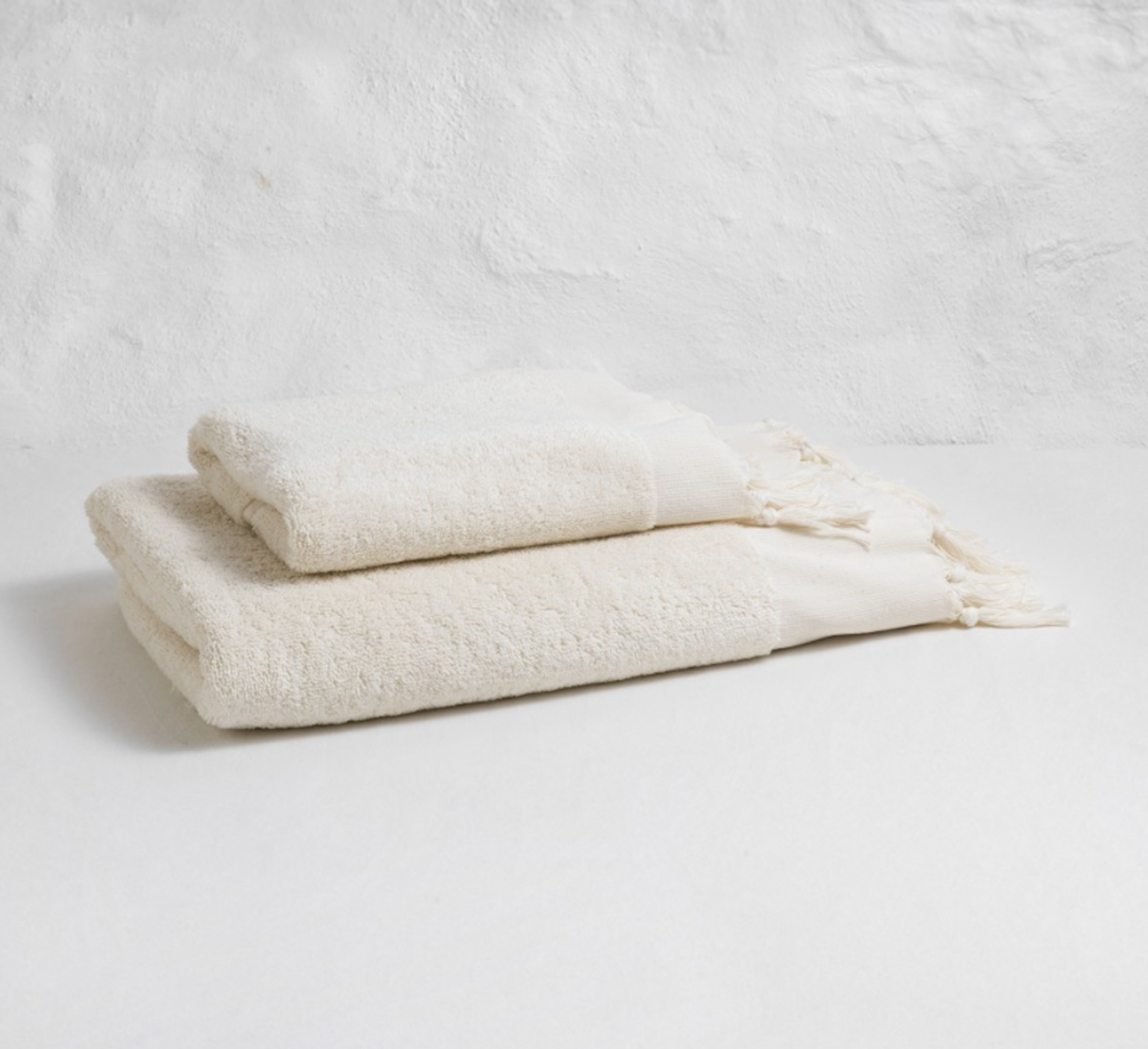Two cream-colored textured towels on a light gray background