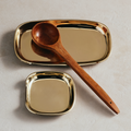 Gold spoon rest with a wooden spoon on a light background