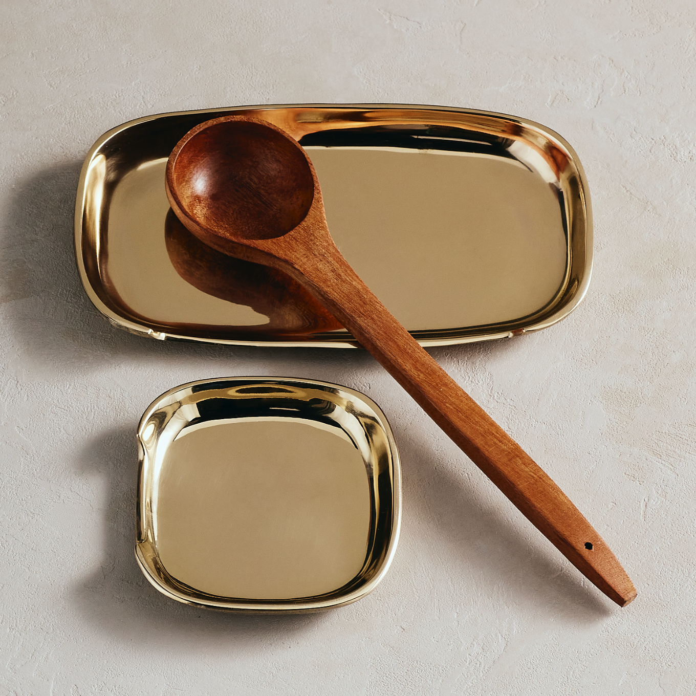 Gold spoon rest with a wooden spoon on a light background