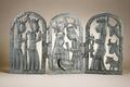Decorative metal wall art with religious figures on a beige background