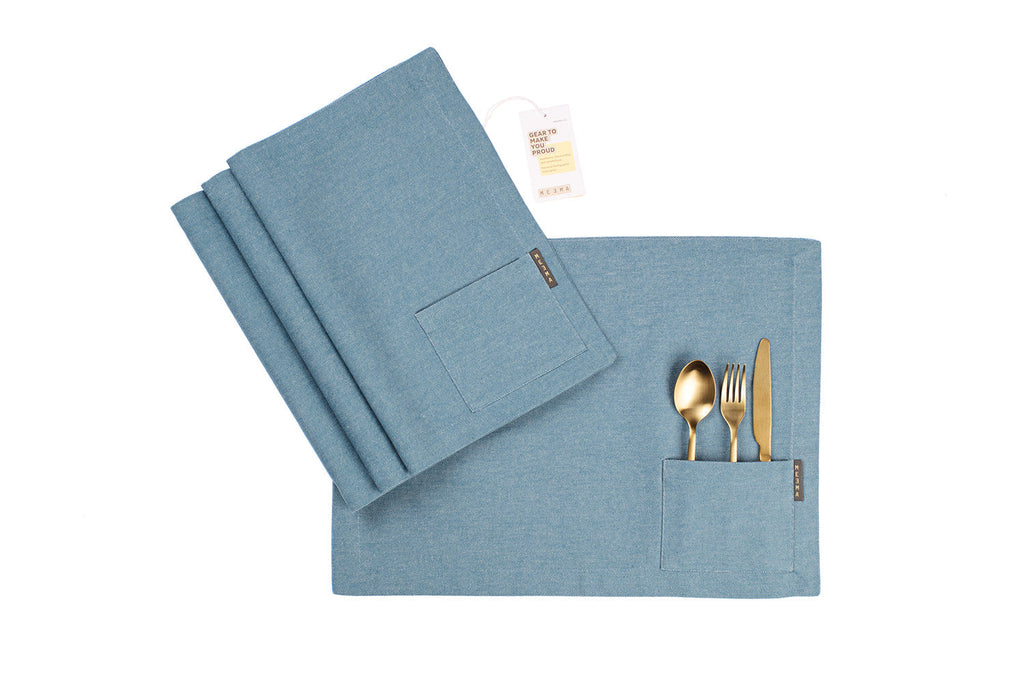Blue napkin/placemat with cutlery pocket and folded napkin on a white background