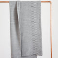 Folded patterned blankets on a copper rack against a white background