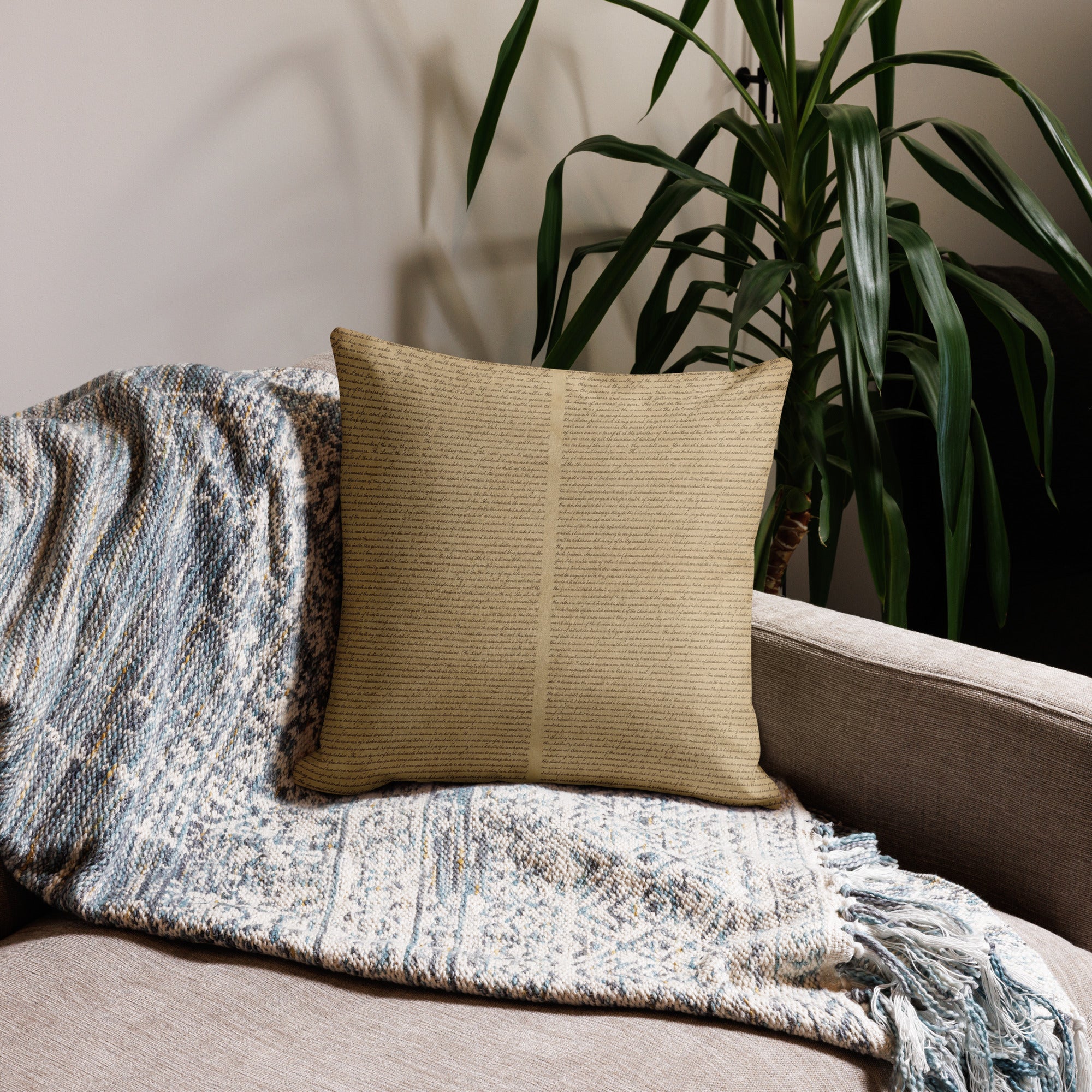 Luxury Comfort Pillow with a textured beige cover resting on a cozy patterned throw blanket on a neutral sofa, next to a tall green indoor plant, creating an elegant and inviting home decor setting.
