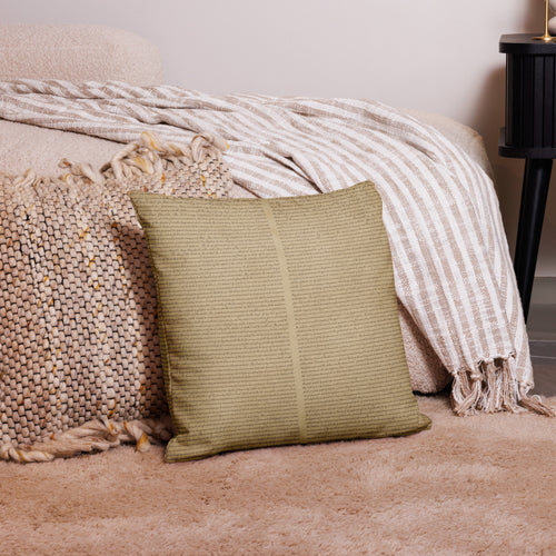 Luxury Comfort Pillow in a soft, textured olive green fabric placed on a beige shaggy rug next to woven and striped neutral-toned throws in a cozy home decor setting.