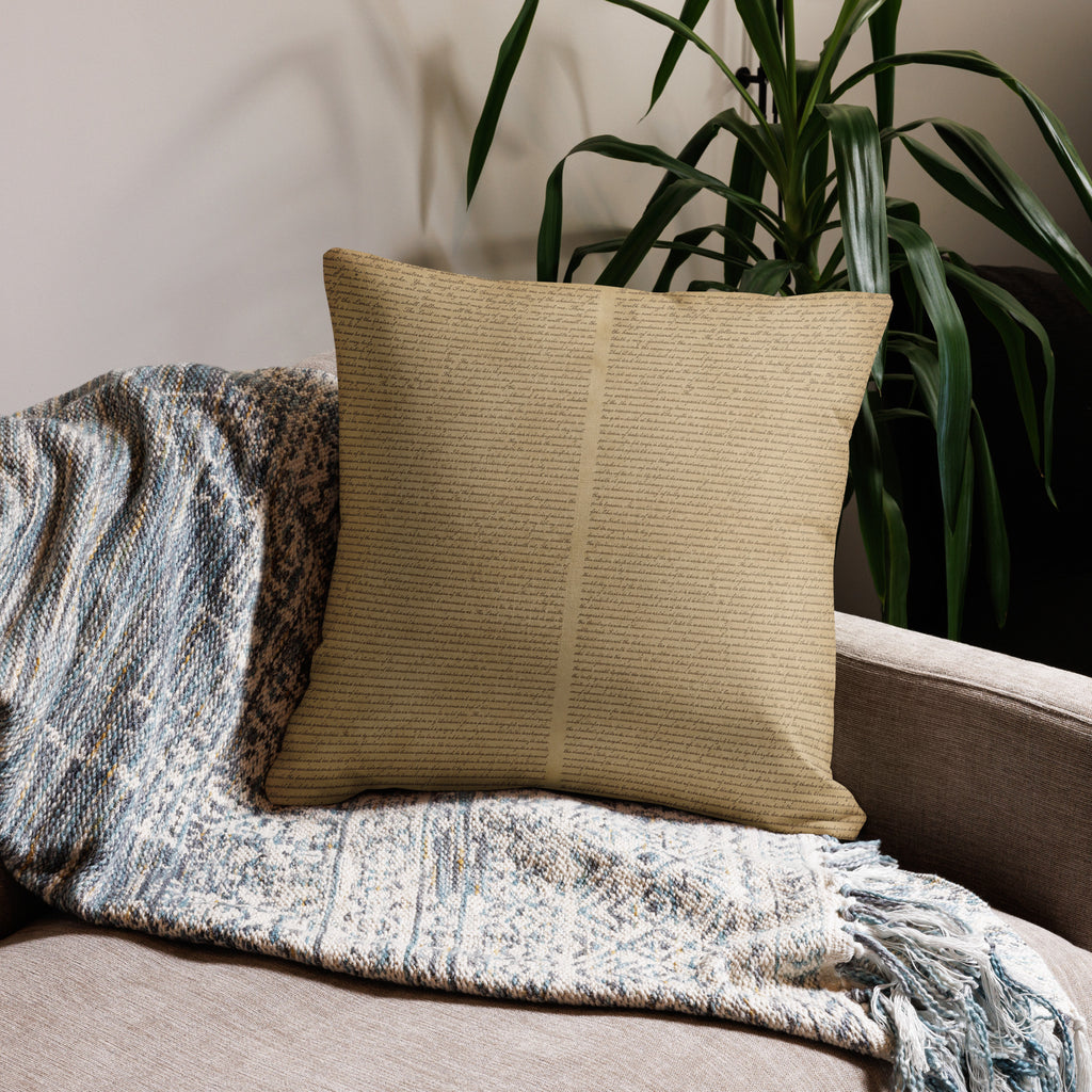 Luxury Comfort Pillow with a subtle text pattern placed on a cozy textured throw blanket on a sofa, next to a green leafy plant in a stylish living room setting.