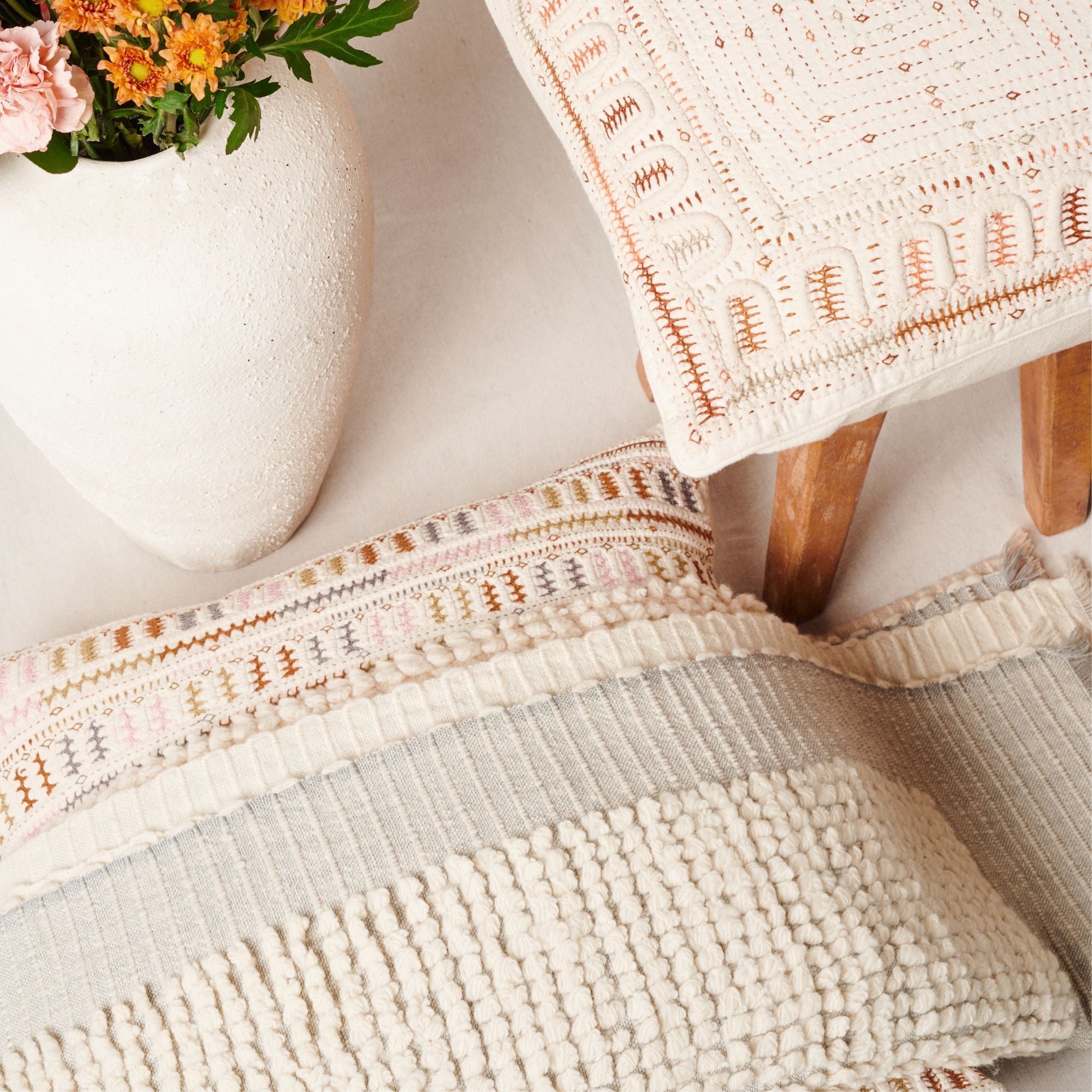 Textured pillows owith a vase of flowers in the background