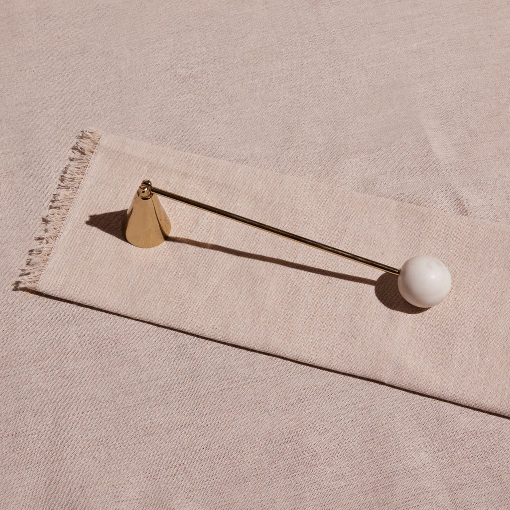 Decorative object with a white sphere and gold accents on a beige fabric background