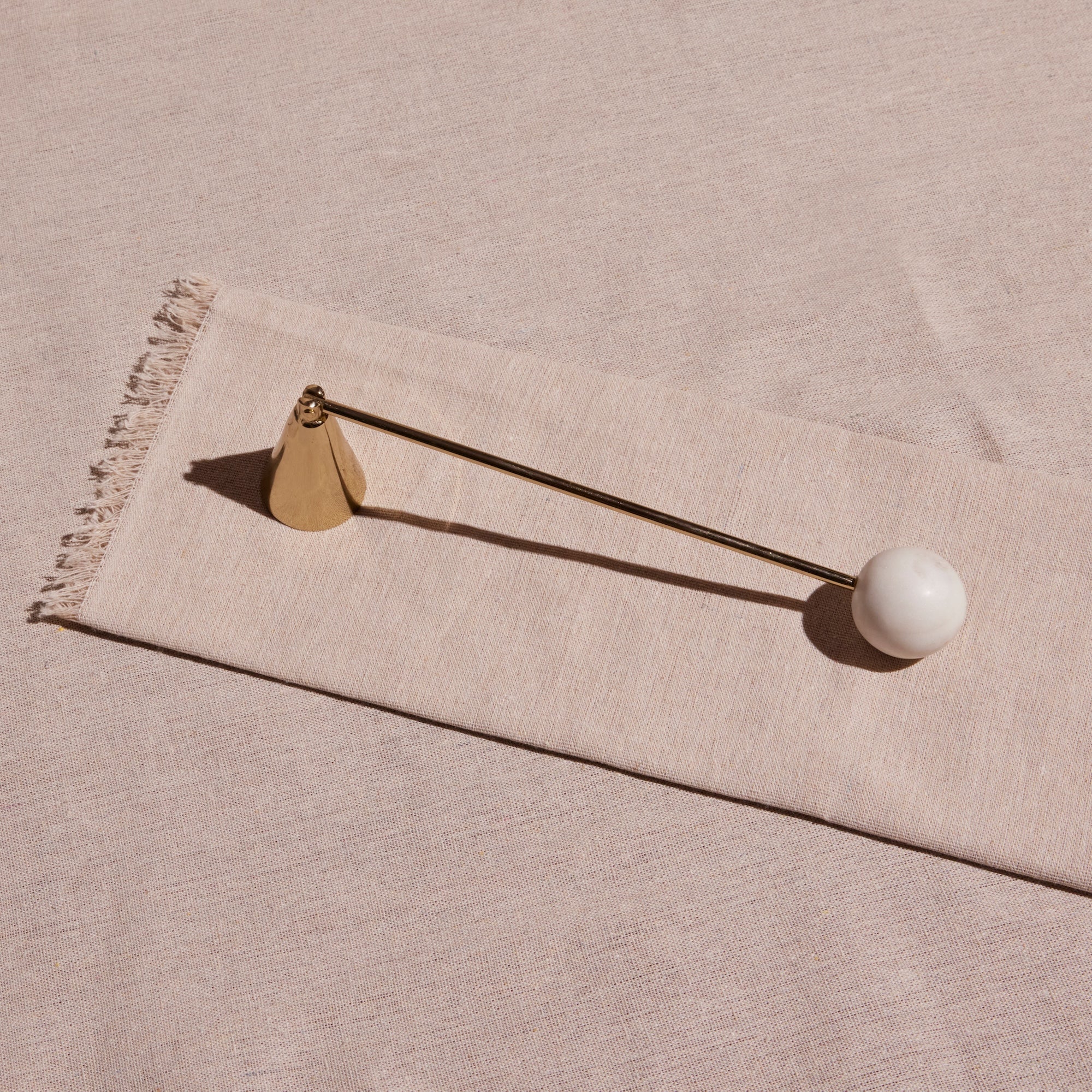 Decorative object with a white sphere and gold accents on a beige fabric background