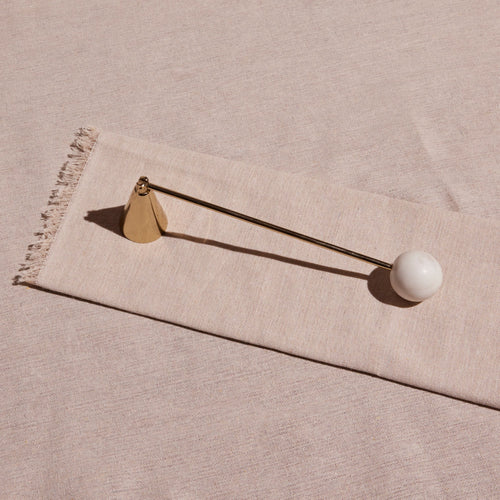 Decorative object with a white sphere and gold accents on a beige fabric background