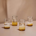 Four glasses with layered liquids on a neutral background
