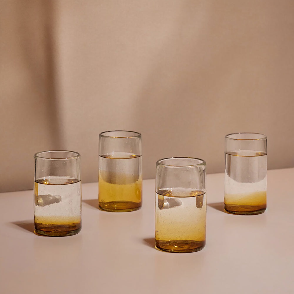 Four glasses with layered liquids on a neutral background