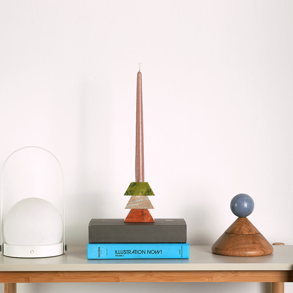 Decorative objects including a candle holder, books, and a small globe on a table with a white background