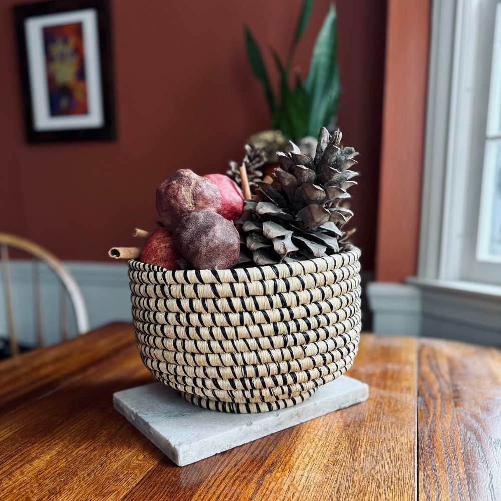 Decorative woven basket with fruits and pinecones on a wooden table