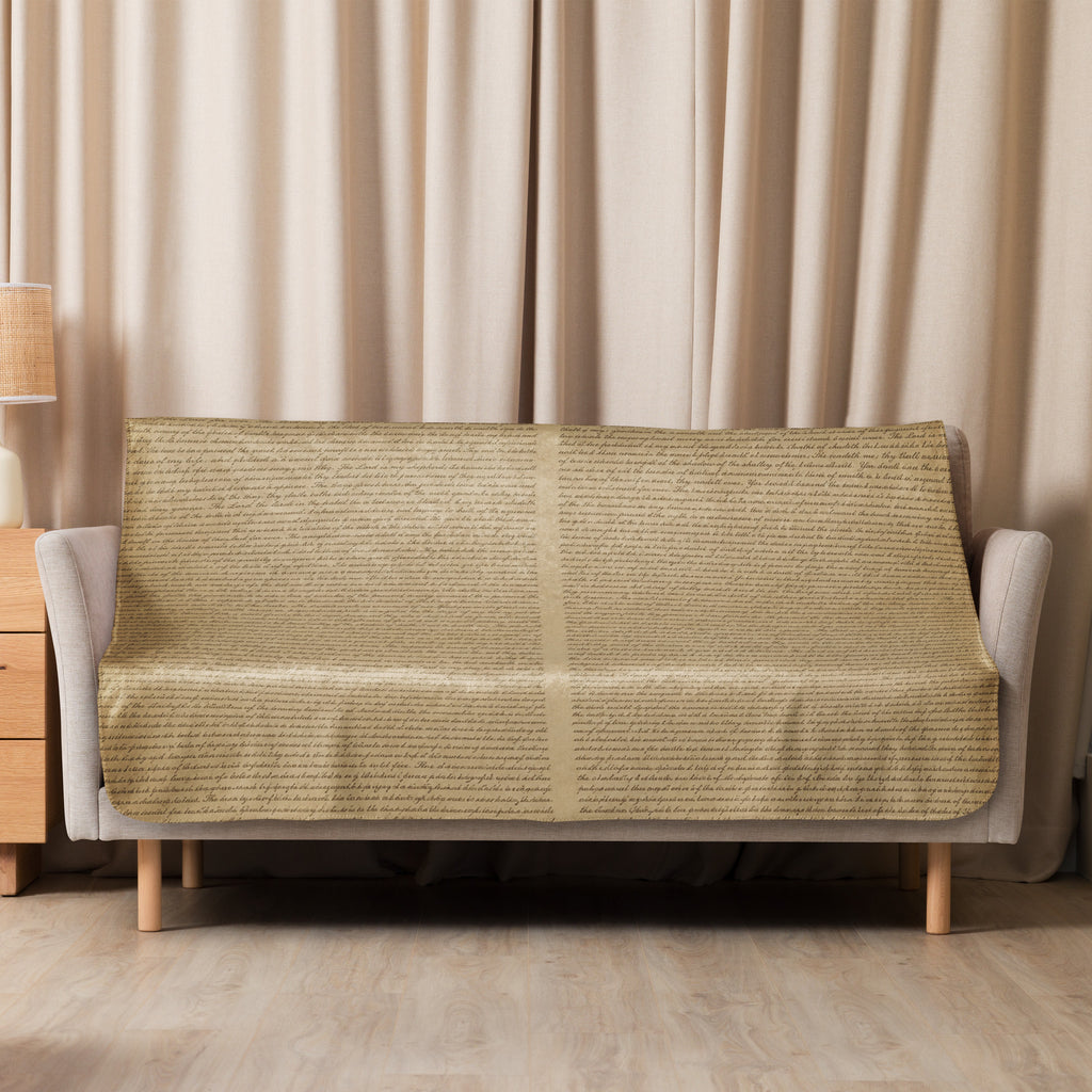 Luxury Sherpa Throw Blanket in tan color draped over a modern beige sofa in a cozy living room setting with wood flooring and light curtains.