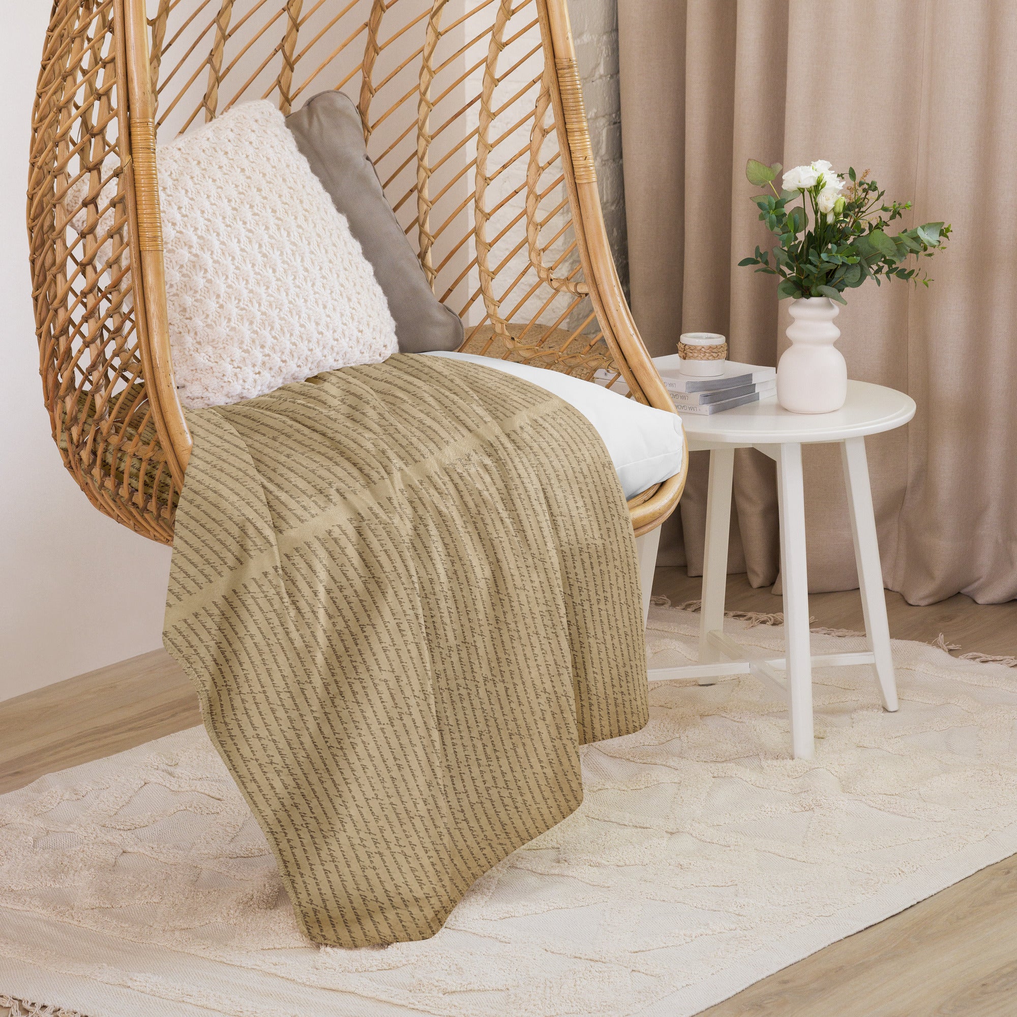 Luxury Sherpa Throw Blanket draped over a woven hanging chair with white cushion, next to a white side table holding a small vase of flowers and decorative items in a cozy room setting.