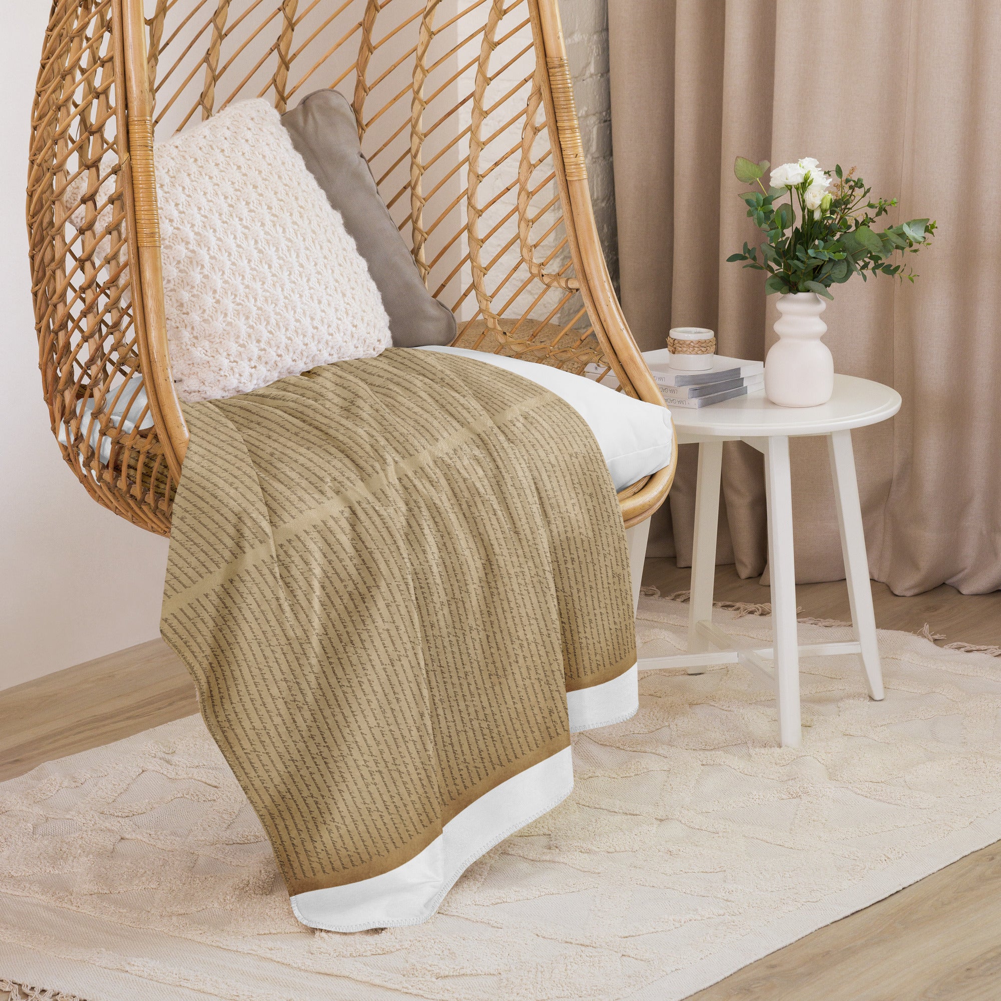 Luxury Sherpa Throw Blanket — Signature Edition draped over a woven hanging chair with textured pillows, next to a white side table with a vase of flowers in a cozy, elegant room setting.