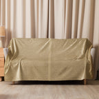Luxury Sherpa Throw Blanket draped over a sofa in a cozy living room setting, featuring a soft tan color and subtle text pattern, complementing elegant home decor.