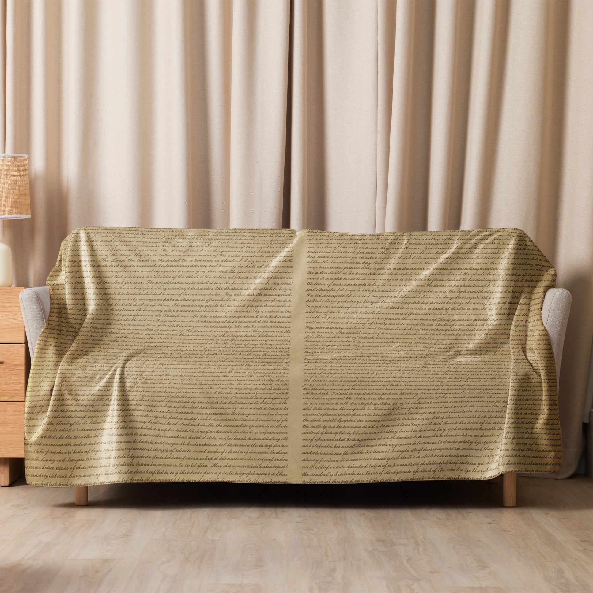 Luxury Sherpa Throw Blanket draped over a sofa in a cozy living room setting, featuring a soft tan color and subtle text pattern, complementing elegant home decor.