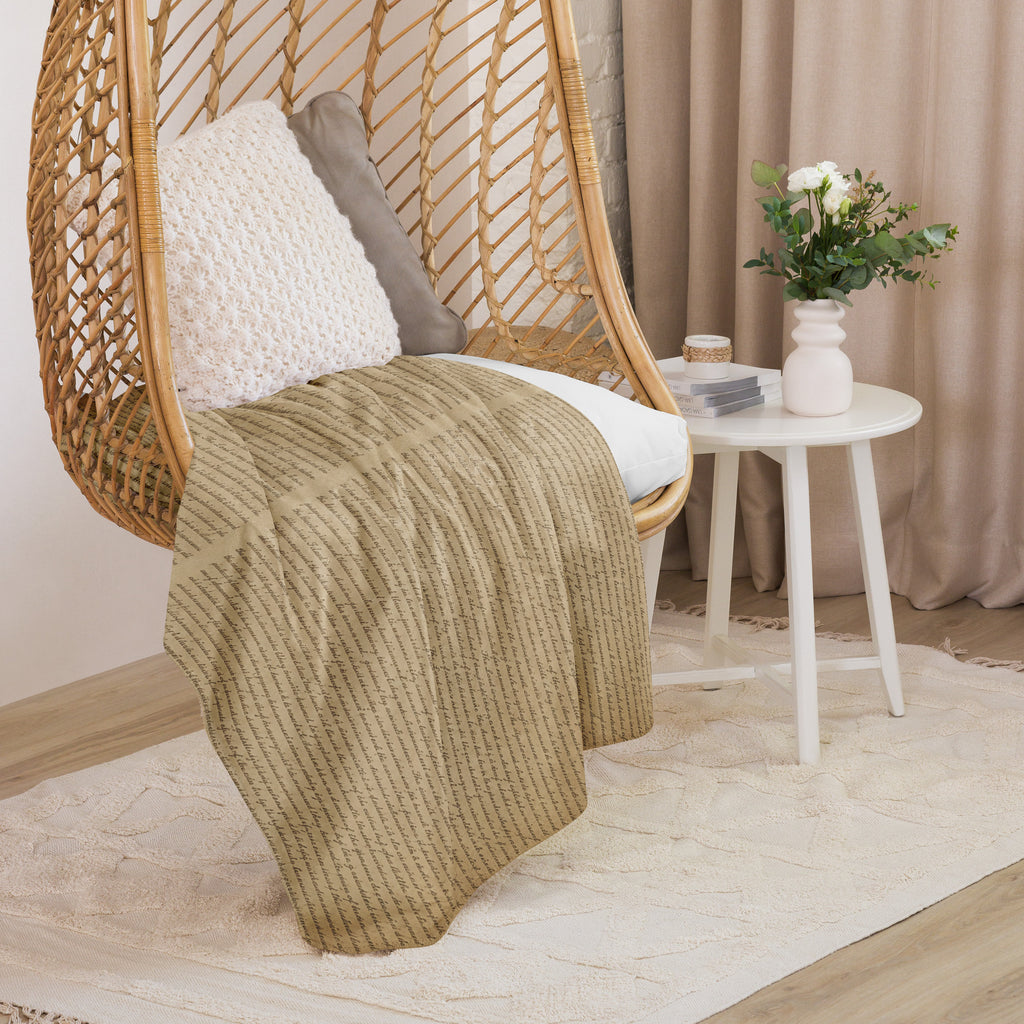 Luxury Sherpa Throw Blanket draped over a woven chair with textured cushions beside a white round table holding a vase of flowers, set in a cozy, neutral-toned room.
