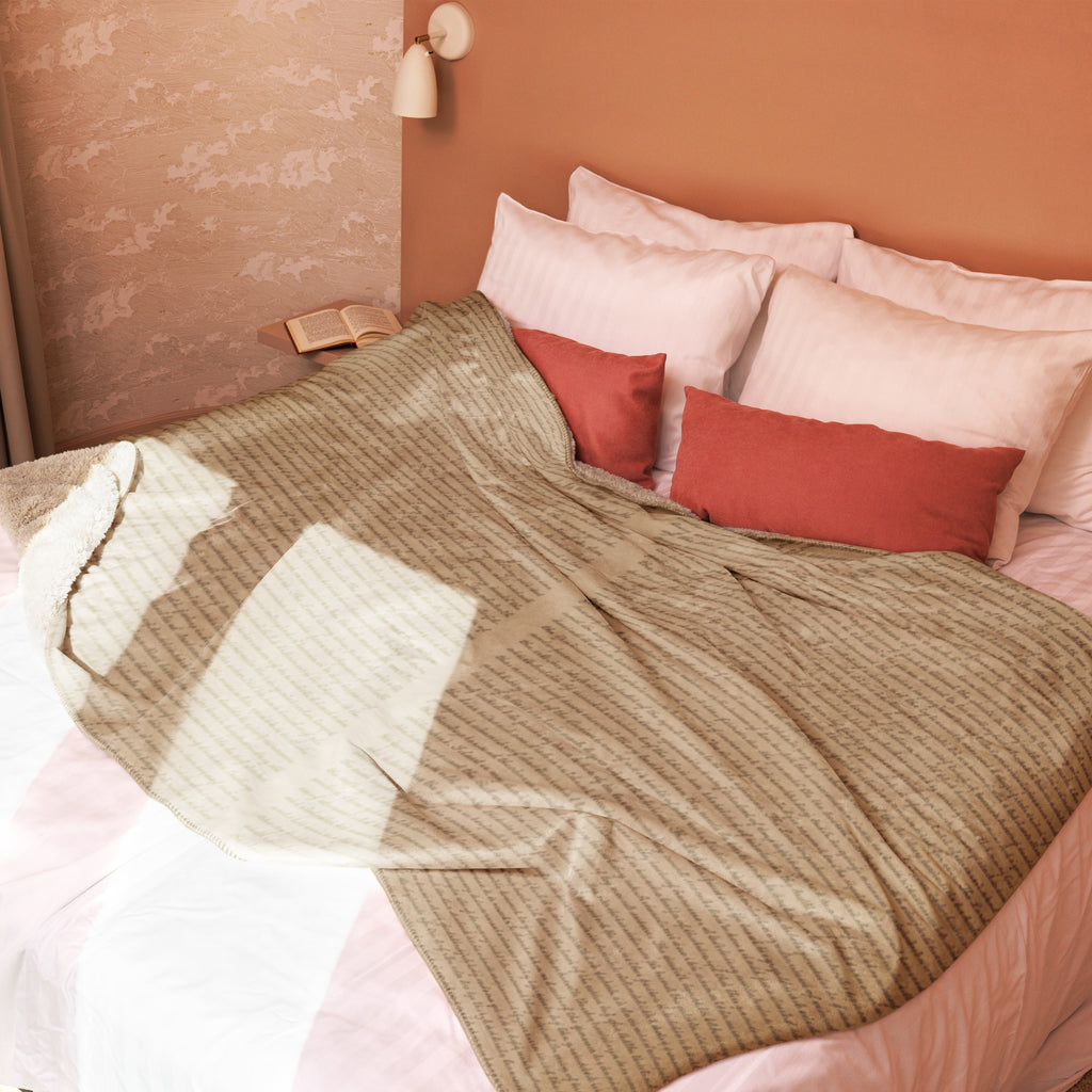 A cozy tan Luxury Sherpa Throw Blanket — Signature Edition draped over a bed with white pillows and rust-colored accent cushions in a warm, stylish bedroom setting.