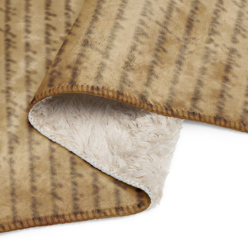Folded tan throw blanket with soft white sherpa lining, featuring an elegant script pattern, showcasing the cozy Luxury Sherpa Throw Blanket — Signature Edition.